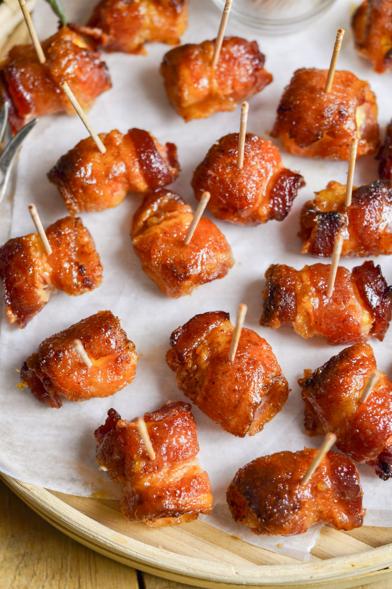 bacon wrapped pineapple bites on platter with toothpicks stuck in each